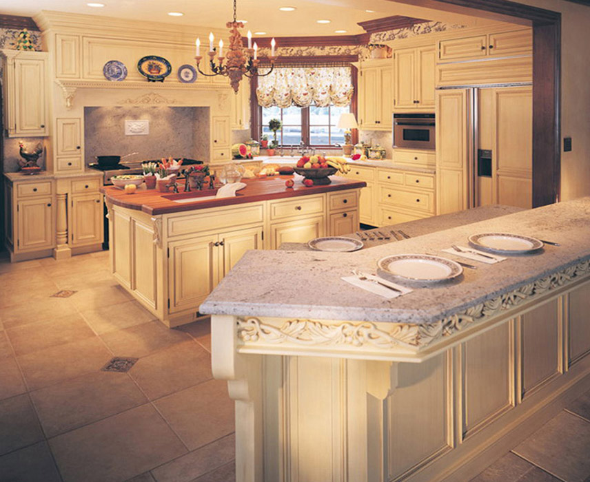 Custom kitchen with wood range hood, carved moldings, and seating area. 